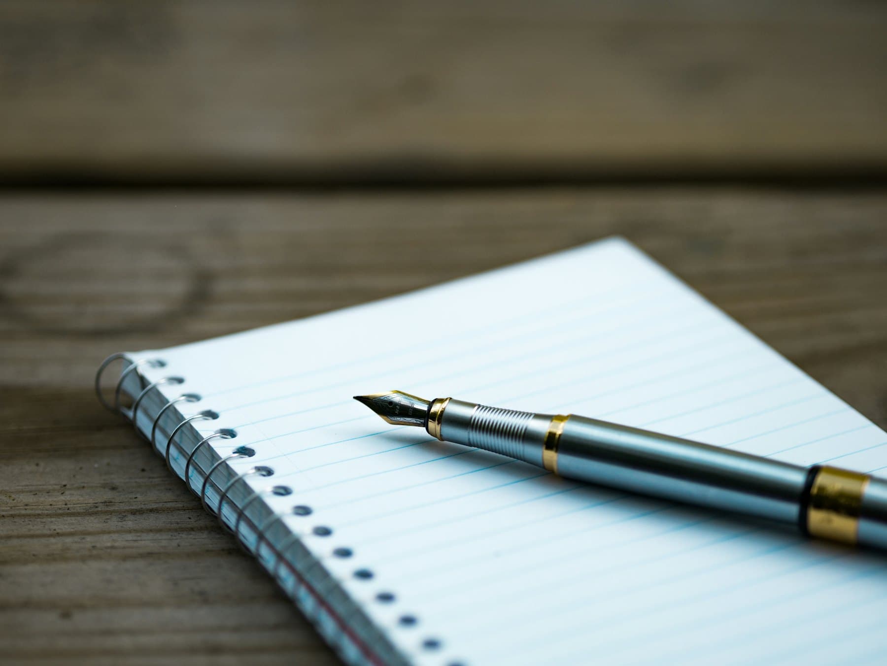 A fountain pen resting on an open lined notebook