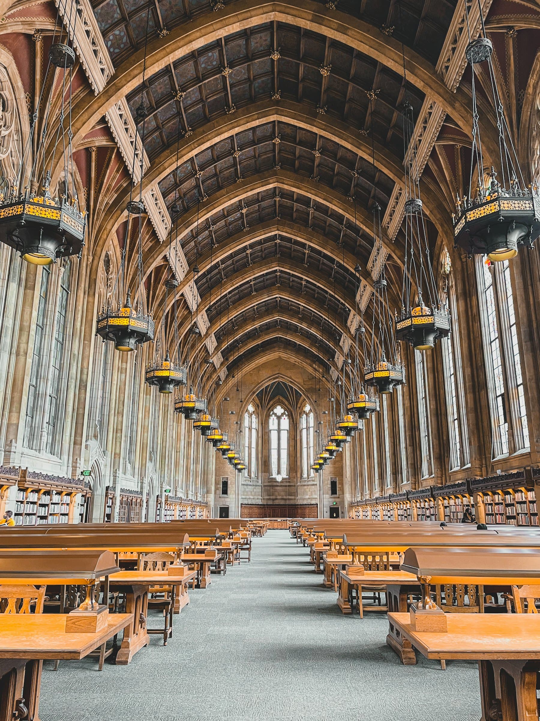 A long reading room lined with study desks beneath arched windows